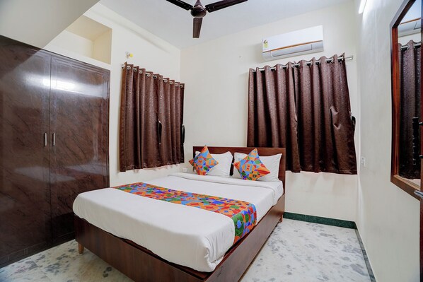 Un dormitorio con cama, cortinas, armario y aire acondicionado.