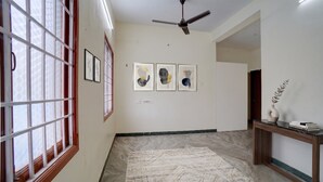 Un pasillo con ventilador de techo, obras de arte enmarcadas en la pared, una consola con un florero y libros, y un tapete estampado en el suelo.