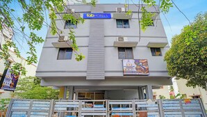 Un edificio de varios pisos con un letrero que dice 'fabHOTELS' y un gran anuncio de 'B2N SEMBAKKAM'.