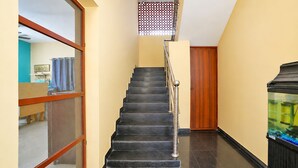 Una escalera con barandilla de metal, una puerta de madera al final y un acuario a la derecha.