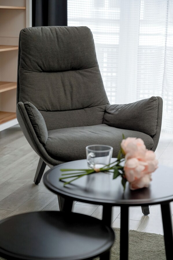 A modern armchair with a glass of water and a flower on a small table.