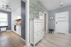 Une cuisine moderne avec des meubles blancs, un mur orné d’un motif et un plancher en bois.