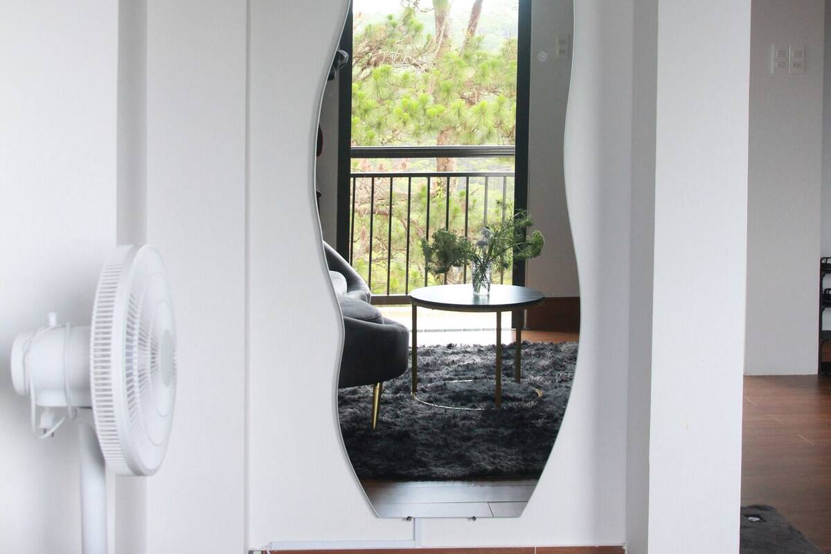 A room with a unique arched doorway leading to an outdoor area with a table and chairs, a fan, and a potted plant.