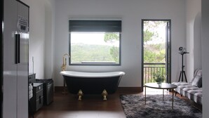 A modern bathroom with a freestanding bathtub, a window with a view, a sofa, and a tripod-mounted camera. - Thai Bao Chau 3  (Xuan Huong - Da Lat)