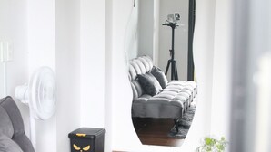 A modern living room with a grey sofa, a black and white marble coffee table, and a mirror reflecting a bed with a tripod. - Thai Bao Chau 3  (Xuan Huong - Da Lat)