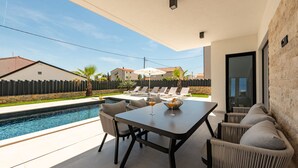 A modern outdoor patio with a pool, lounge chairs, and a dining table. - Villa Kri to Zadarvillas (Privlaka)