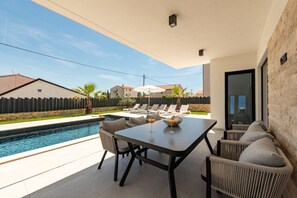 Eine moderne Außenpatio mit Pool, Liegestühlen und einem Esstisch.
