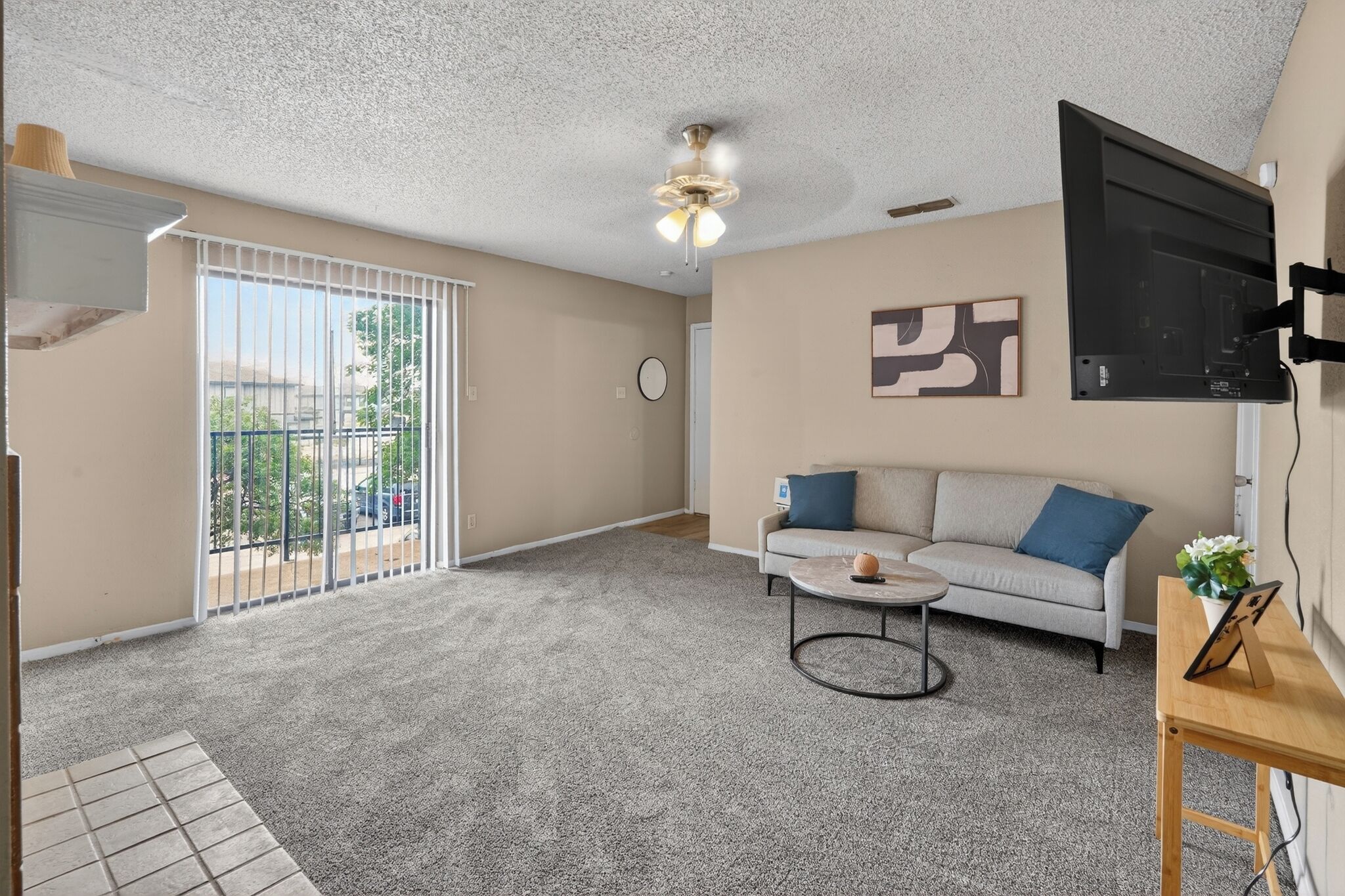 A living room with a sofa, coffee table, and a TV mounted on the wall.