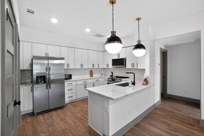 A modern kitchen with stainless steel appliances, white cabinetry, and pendant lighting. - Stylish 1-bedroom featuring contemporary finishes. (Austin)