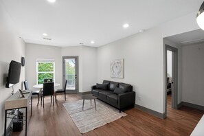 Ein modernes Wohnzimmer mit einer Couch, einem Couchtisch, einem Fernseher und einem Essbereich mit Stühlen.
