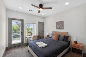 Ein Schlafzimmer mit Bett, Nachttischen, Deckenventilator und einem Fenster mit Jalousien.