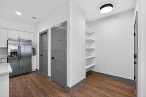 Eine moderne Küche mit Kühlschrank aus Edelstahl, Doppeltüren und integrierten Regalen.
