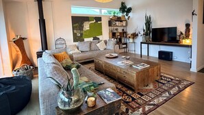 A modern living room with a sofa, coffee table, and a TV. - Brilliantly located, warm & stylish family home with garden and tonnes of space (Auckland)