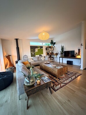 A modern living room with a sofa, coffee table, and a TV. - Brilliantly located, warm & stylish family home with garden and tonnes of space (Auckland)