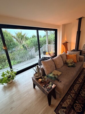 Een moderne woonkamer met een groot raam, een bank, een salontafel en een open haard.