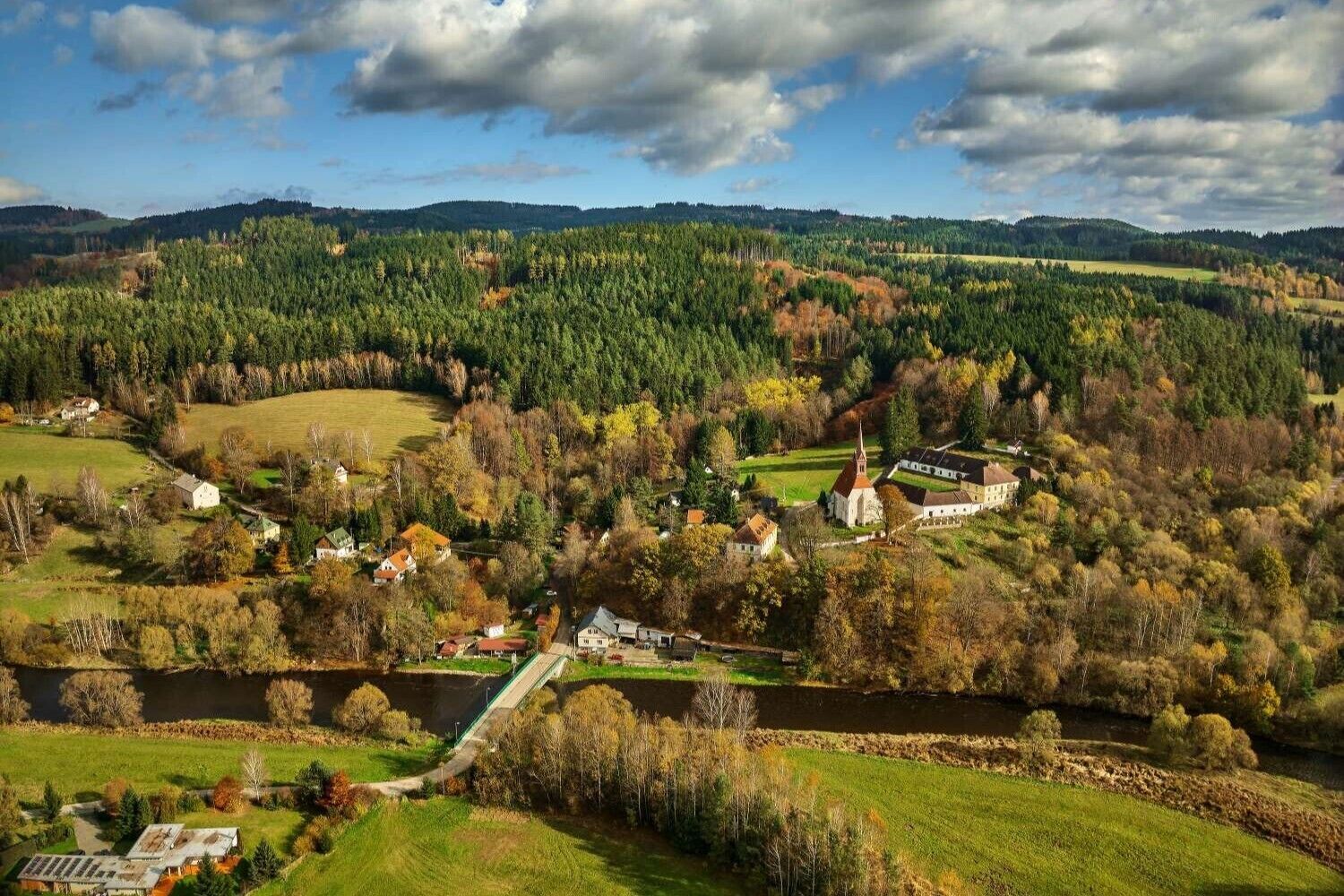 A rural landscape with a river, scattered houses, and a church.