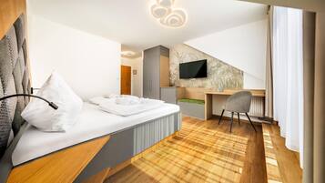 Una habitación de hotel moderna con cama, escritorio, silla y televisor montado en la pared.