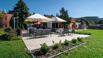 A patio area with outdoor seating, umbrellas, and a garden.