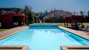 Una piscina rectangular con superficie de agua azul cristalina, rodeada por una terraza de madera.