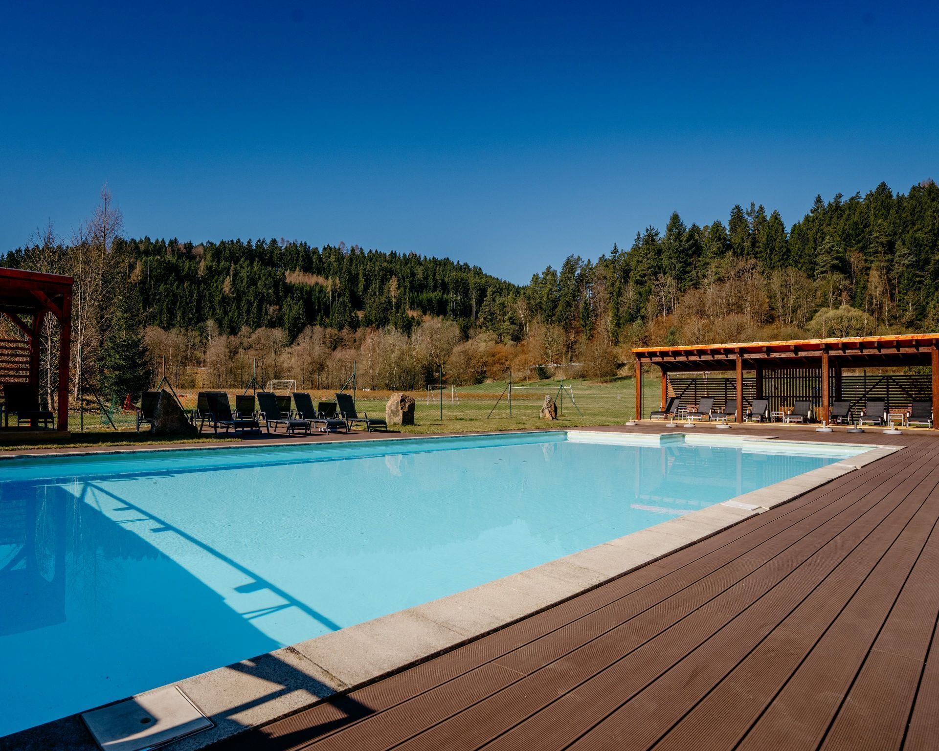 Una piscina con sillas de descanso y una terraza de madera.