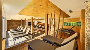 Un spa moderne avec un décor intérieur en bois, des chaises longues et une vue sur la forêt.