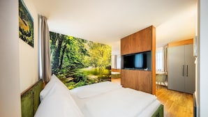 Une chambre d’hôtel avec un lit, une télévision, un bureau et une grande fresque représentant une forêt sur le mur.