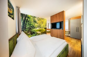 Una habitación de hotel con cama, televisión, escritorio y un gran mural de un bosque en la pared.
