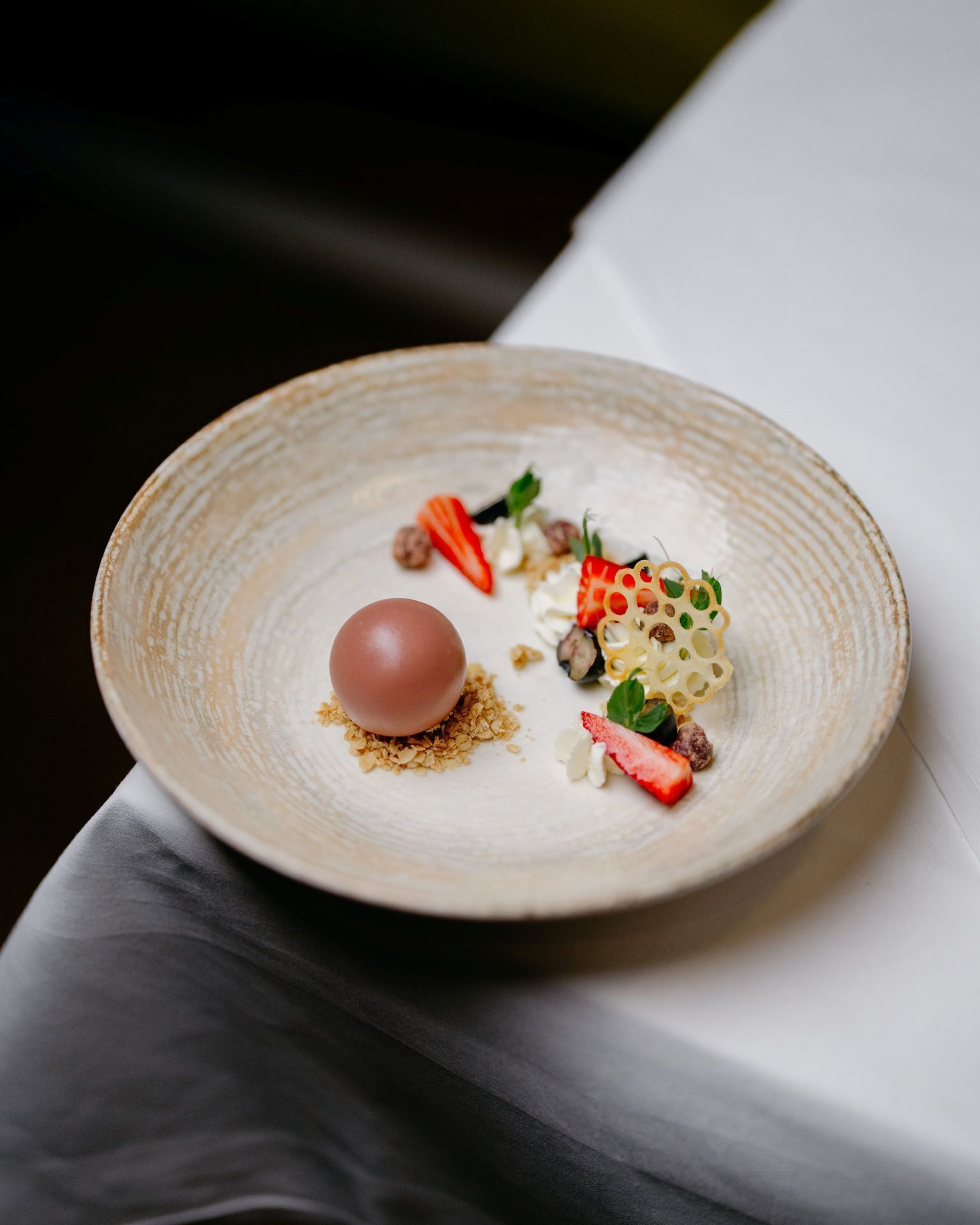 A dessert on a ceramic plate with a white tablecloth.