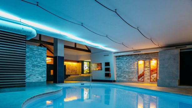 Une piscine intérieure à bords incurvés, avec des murs en pierre et un escalier menant à un niveau supérieur.