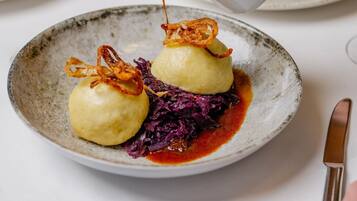 A plate with dumplings, red cabbage, and a sauce being poured over them.