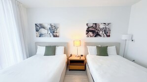 Ein Hotelzimmer mit zwei Betten, einem Nachttisch mit Lampe und Bildern an der Wand.