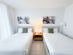 Ein Hotelzimmer mit zwei Betten, einem Nachttisch mit Lampe und Bildern an der Wand.