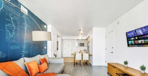 Un salon moderne avec un canapé, un coin repas et une cuisine en arrière-plan.