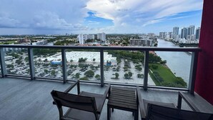 Un balcón con vista a un paisaje urbano, que incluye edificios y un río.