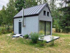 A small, modern house with a sloped roof, a door, and a window. - Tiny House Wrzosowisko (Prościeniec)