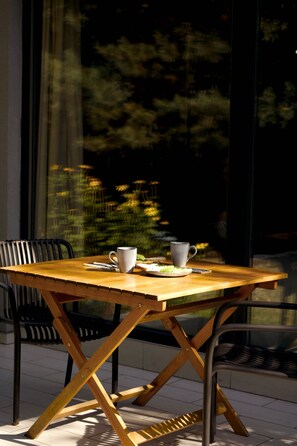Une table en bois avec un cadre en métal, deux chaises et une tasse posée sur la table.
