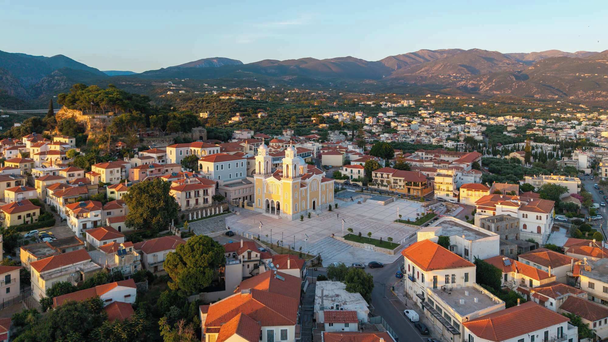A town with a prominent church, residential buildings, and a mountainous backdrop.