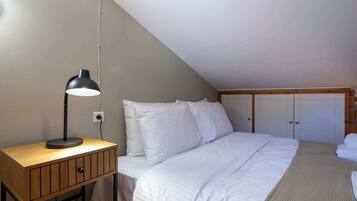 Een slaapkamer met een bed, een bureau met lamp en een kledingkast.