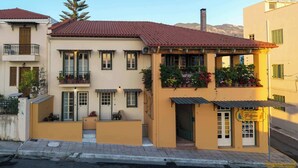 A two-story building with balconies, a small outdoor seating area, and a shop entrance.