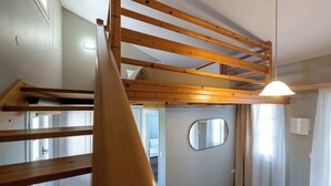 A room with a bunk bed, a mirror, a staircase, and a ceiling light.