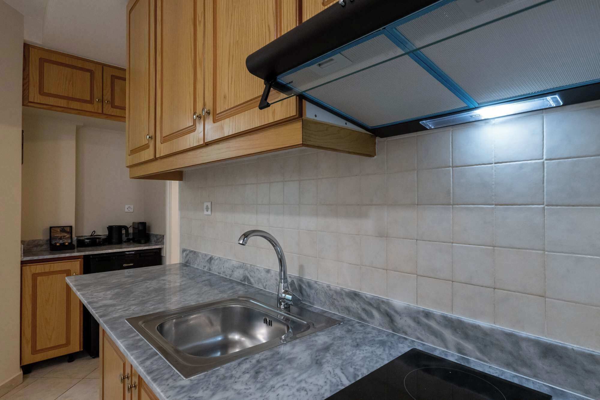 A kitchen with wooden cabinets, a stainless steel sink, and a tiled backsplash.