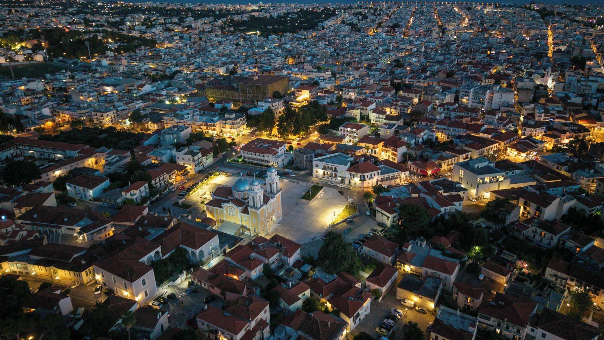 Vista aérea de uma área urbana densamente povoada, com mistura de edifícios residenciais e comerciais, incluindo uma igreja com cúpula em destaque.