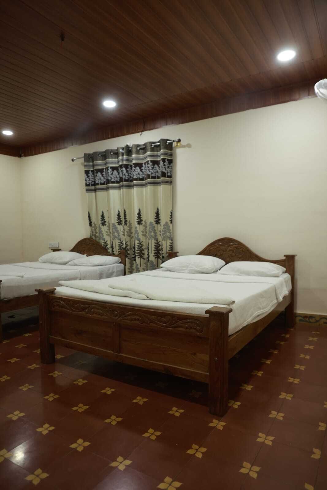 A room with two single beds, a wooden ceiling, and patterned floor tiles.