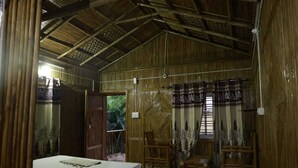 A room with a bed, two chairs, a wooden door, and a window with curtains. - N D Farms (Kanakapura)