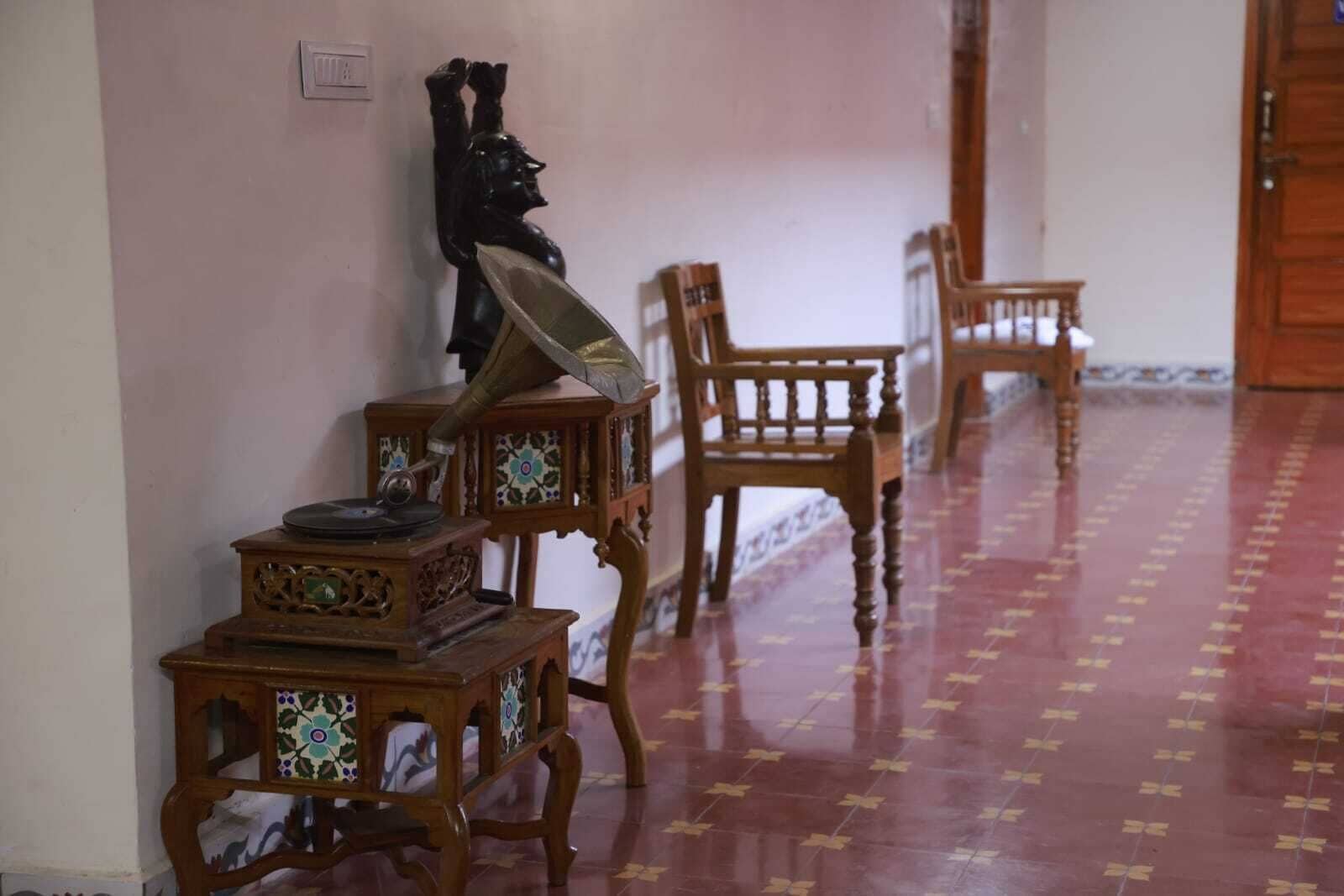 A hallway with patterned flooring, wooden furniture, and a wall-mounted sculpture.