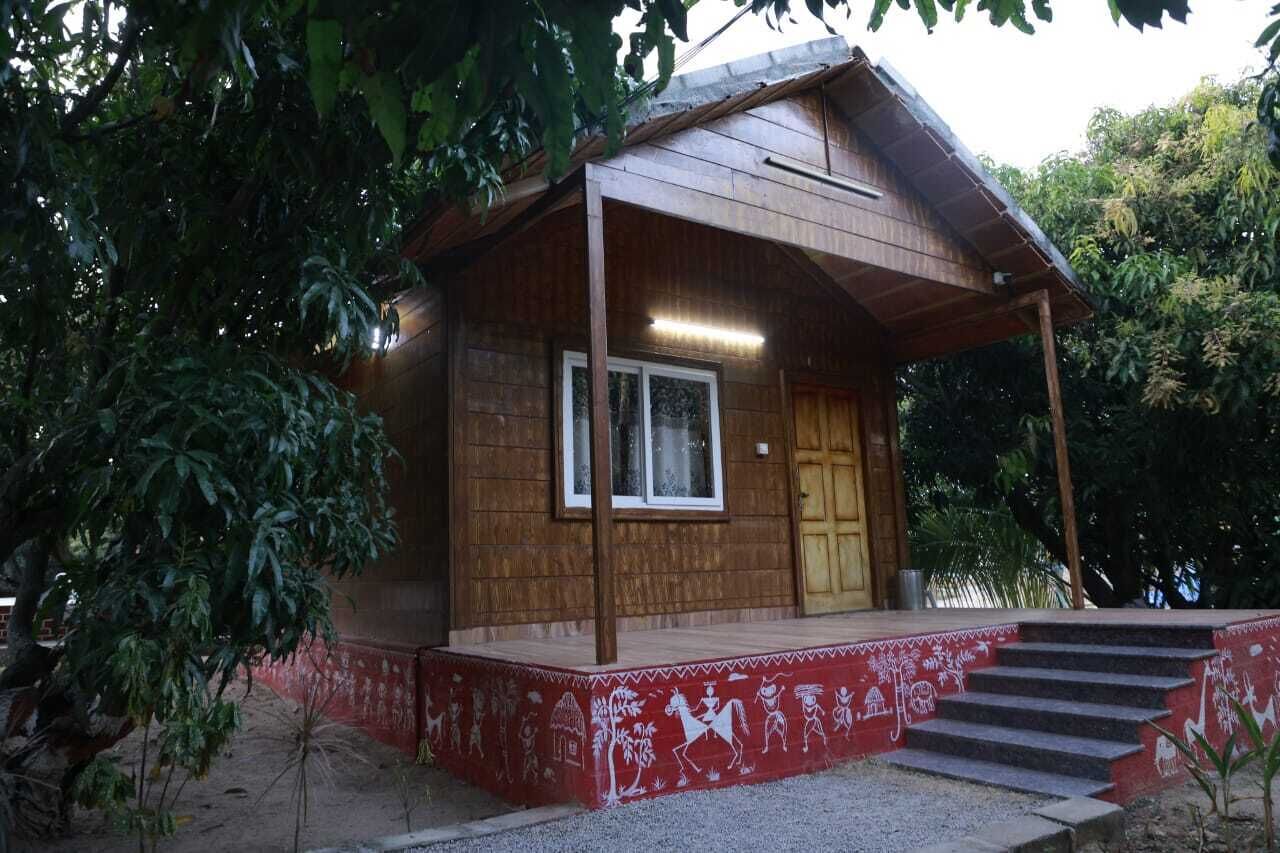 A wooden cabin with a porch, steps, and a window.