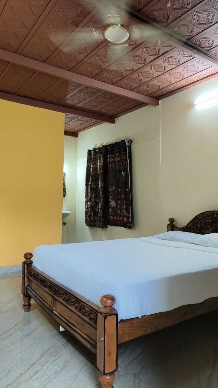 Una habitación con cama de madera, ventilador de techo y cortinas estampadas.