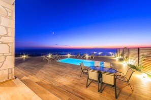 Eine Holzterrasse mit Pool, Liegestühlen und einem Tisch.