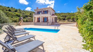 A stone villa with a swimming pool, sun loungers, and a view of the surrounding greenery. - Sunset Vista Villas Deluxe III (Zakynthos)