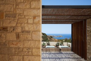 Eine Steinsäule und ein Holz-Pergola mit Blick auf das Meer.